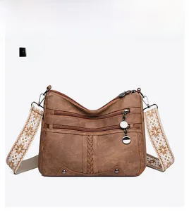 Front view of brown leather crossbody bag with ethnic style embroidered shoulder strap