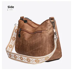 Detail of dark brown vintage crossbody bag with ethnic embroidered strap and multi-zippered pockets