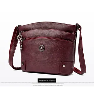 Détail du sac bandoulière bordeaux en similicuir avec texture grainée et poches zippées