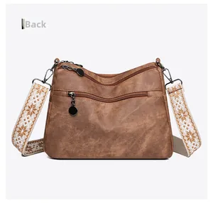 Back view of brown vintage leather crossbody bag featuring multiple zippers and floral strap