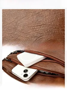 Gros plan sur la texture cuir marron grainé et les compartiments zippés fonctionnels