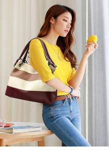 Detail of color-block tote bag with litchi grain leather texture and metallic rings