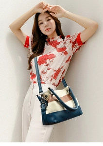 Detail of tricolor leather handbag with navy and beige panels worn by a model