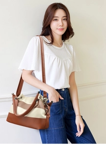 Detail of color-block brown and beige leather shoulder bag worn by model in casual style