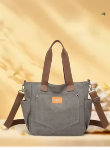 Detail of grey canvas tote bag with brown handles and leather accent on front pocket