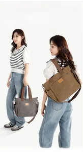 Detail of multi-pocket canvas bag showing handheld and shoulder carry styles
