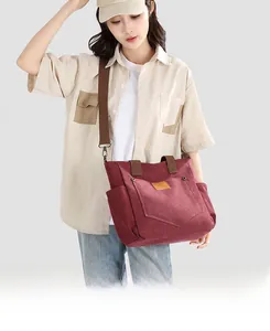 Detail of burgundy thick canvas tote bag featuring multi-pocket design and brown straps