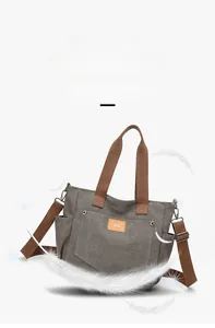 Detail view of grey canvas tote bag with brown handles and orange leather logo patch