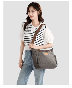Detail of dark grey canvas tote bag featuring front pocket and adjustable brown strap