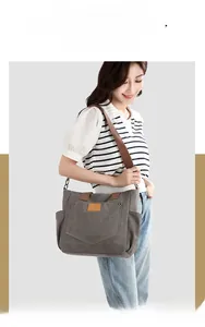 Macro shot of dark grey canvas tote bag showing side pockets and brown fabric strap