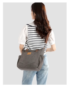Back view of a model carrying the large dark gray canvas tote bag with wide shoulder strap