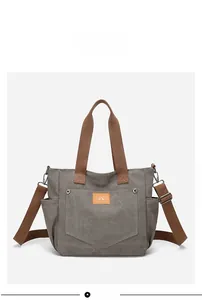 Front view of a grey canvas tote bag with brown straps and multi-pocket design detail