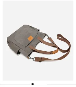 Top view of grey canvas tote bag with brown straps and detachable shoulder strap detail