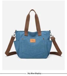 Close-up of sky blue canvas tote bag with brown leather patch and adjustable shoulder strap