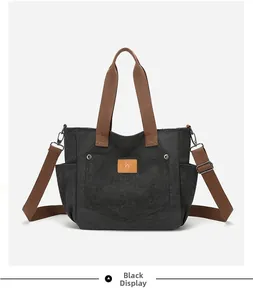 Detailed view of black canvas tote bag with brown fabric handles and leather logo patch