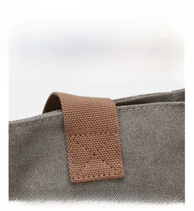 Detail of reinforced X-shape stitching on brown canvas bag handle for extra durability
