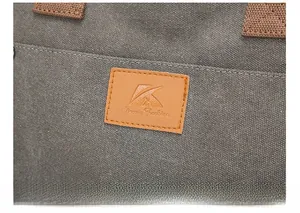 Detail of classic leather logo patch on high-quality grey canvas shoulder bag