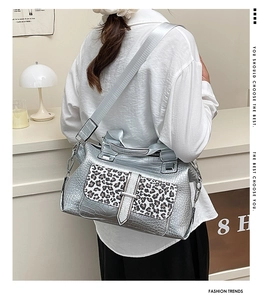 Detail of silver crocodile-embossed handbag with leopard print pocket and wide strap