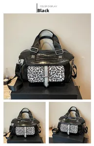Detail view of black crocodile pattern handbag with leopard print flap and wide strap