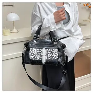 Detail of crossbody bag with black crocodile texture and leopard print pocket