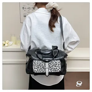 Detail view of crocodile embossed leather shoulder bag with leopard print flap and buckle