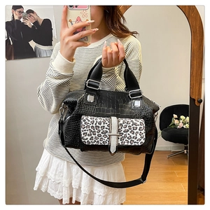 Detail of black crocodile texture handbag with leopard print flap and silver buckle