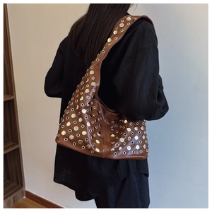 Détail d'un sac porté épaule marron avec rivets argentés et œillets métalliques