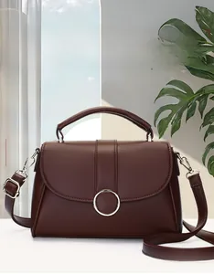 Detail view of a premium dark coffee leather handbag featuring a stylish metal ring buckle