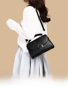 Detailed view of black faux leather shoulder bag with decorative metal ring buckle on flap