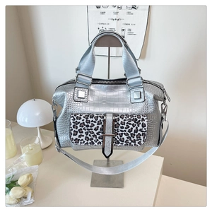 Detailed macro view of silver embossed crocodile pattern handbag with leopard print pocket