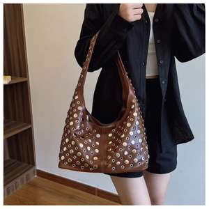 Détail du sac hobo marron vintage avec rivets métalliques ronds porté à l'épaule