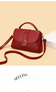 Detailed macro view of wine red leather handbag featuring a large gold circular metal buckle