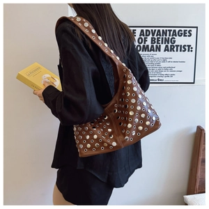 Détail du sac bandoulière en cuir marron avec rivets argentés et œillets métalliques