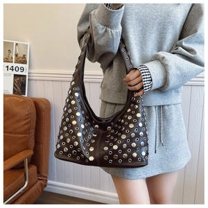 Détail du sac à bandoulière marron vintage avec clous métalliques et œillets argentés