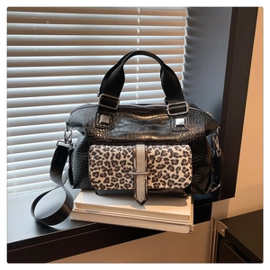 Detail of black crocodile texture handbag featuring a stylish leopard print front pocket