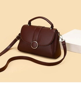 Detail of dark brown leather handbag with large metal ring and adjustable strap