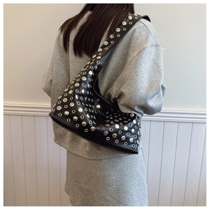 Détail du sac seau noir punk avec œillets métalliques argentés et rivets sur la bandoulière