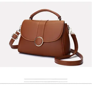 Detail of classic brown leather handbag featuring a stylish gold circular metal buckle