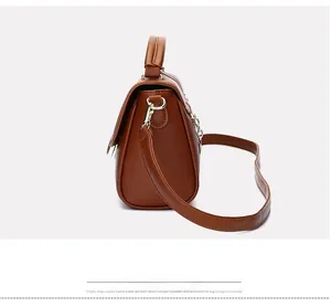 Detail of dark brown leather handbag showing accordion structure and gold metal buckle