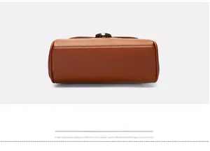 Detail of brown leather handbag featuring clean stitching and round metal buckle detail