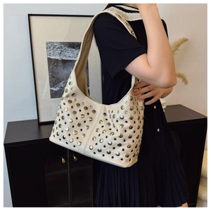 Détail du sac à bandoulière beige avec rivets ronds argentés et œillets métalliques punk