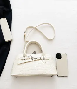 Detailed view of white crocodile pattern handbag with metal buckle and smartphone for size