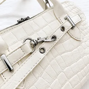 Detail of crocodile embossed leather and polished silver hardware on cream shoulder bag