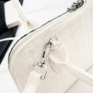 Detail of silver zipper and detachable strap hook on white crocodile pattern leather bag