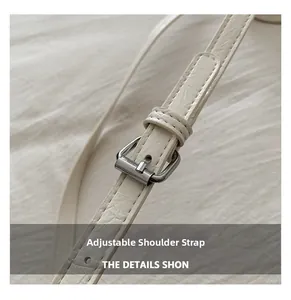 Detail of adjustable off-white crocodile embossed leather shoulder strap with silver buckle