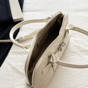 Detail view showing large interior space with brown lining and zip pocket of white handbag