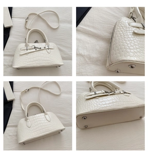 Detail view of cream crocodile embossed leather handbag with silver hardware and studs