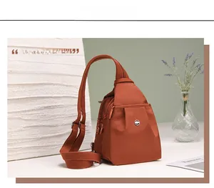 Dettaglio della borsa a tracolla arancione in tessuto Oxford con zip e logo centrale