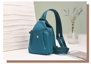 Dettaglio dello zaino in nylon color ottanio con cerniere multiple e logo d'argento