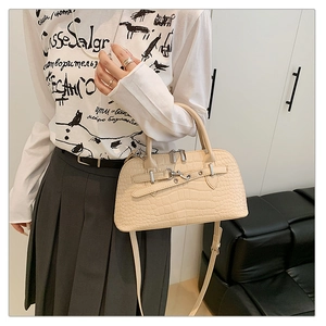 Close-up of beige crocodile embossed handbag with silver clasp and top handles